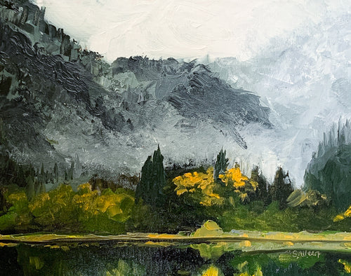 Oil painting of a calm lake bordered by tall pine trees and a rocky shoreline, with soft fog draping distant hills. Gentle light suggests early morning, evoking a quiet sense of awakening in nature.